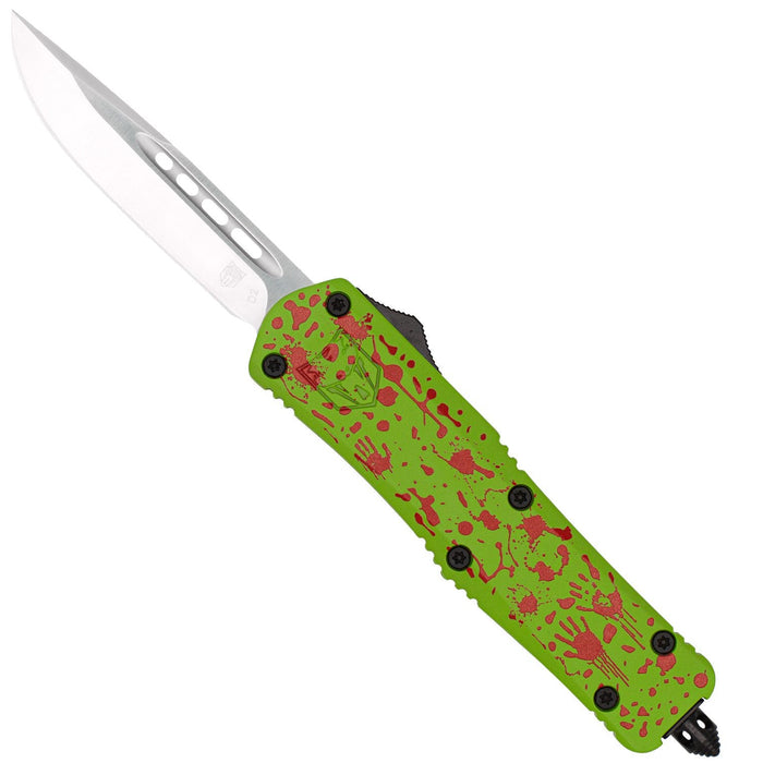 A folding pocket knife with a silver blade and a textured green handle decorated with red splatter patterns, shown against a plain white background.