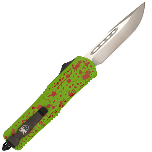 A tactical folding knife with a bright lime green handle featuring red splatter and cross motifs, and a silver drop-point blade, shown diagonally on a plain white background.